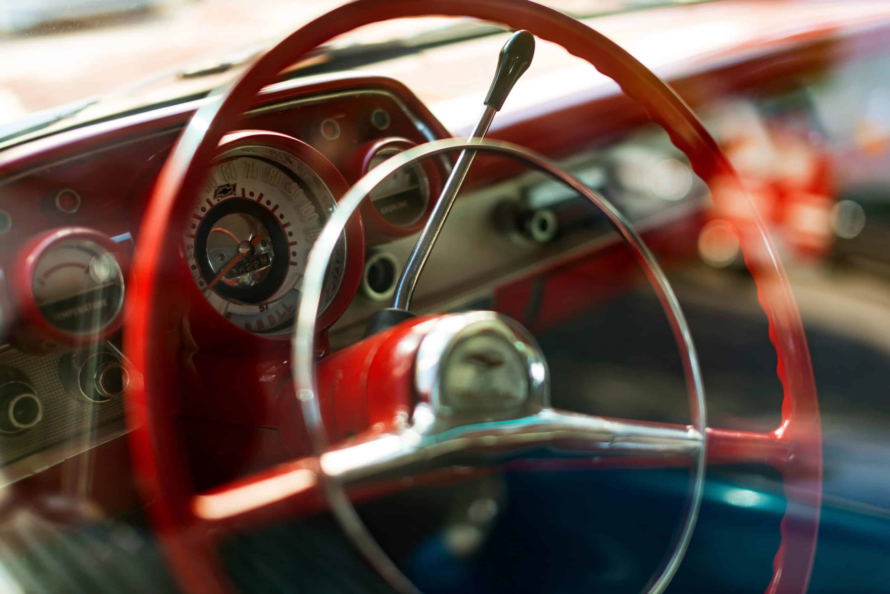 Steering wheel view of a Red colored 1957 Chevrolet.